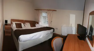 a bedroom with a bed and a desk and a television at The Gremlin Lodge in Brecon