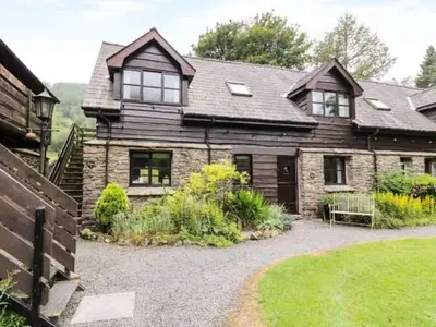 a large brick house with a garden in front of it at Lake Cottages at Cwm Chwefru in Llanafan-fawr