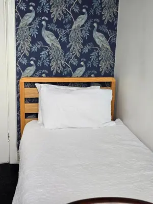 a bedroom with a bed with a blue and white wallpaper at Bluebells guest house in Barmouth