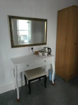 a white dressing table with a mirror and a stool at Bluebells guest house in Barmouth