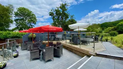 a patio with tables and chairs and a red umbrella at Hafan Artro in Llanbedr
