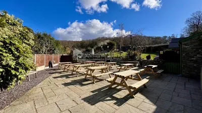 a group of wooden picnic tables on a patio at Hafan Artro in Llanbedr