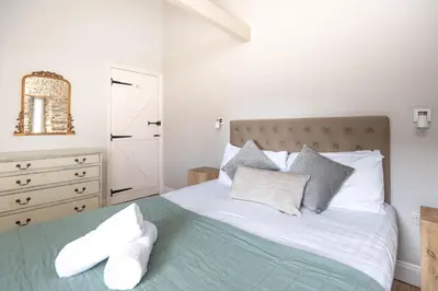 a bedroom with a bed with white sheets and pillows at Granary Cottage with hot tub on organic farmland in Lampeter