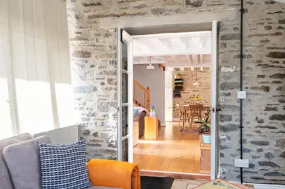 an open door into a living room with a stone wall at Granary Cottage with hot tub on organic farmland in Lampeter