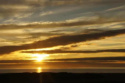 a sunset over the water with the sun in the sky at Sunray Suites in Barmouth