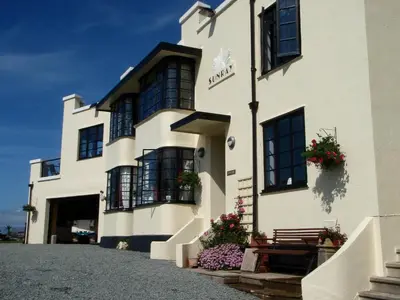 a white building with a bench in front of it at Sunray Suites in Barmouth