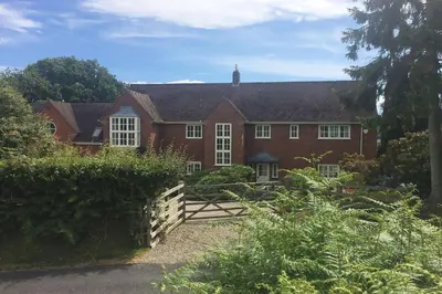 a red brick house with a fence in front of it at The Oaks in Church Stretton
