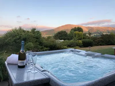 a bottle of wine sitting on a table next to a hot tub at The Oaks in Church Stretton
