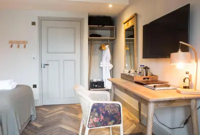 a bedroom with a desk and a bed and a room at George III Hotel in Penmaenpool