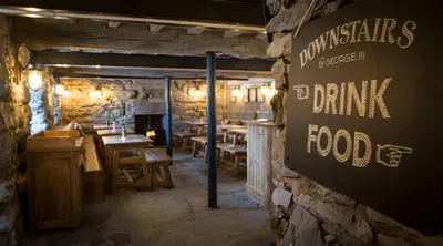a restaurant with tables and a sign on the wall at George III Hotel in Penmaenpool