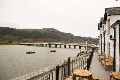 two boats in a river with a bridge in the background at George III Hotel in Penmaenpool