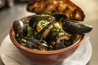 a bowl of mussels on a plate with a bread at The Castle Hotel in Llandovery