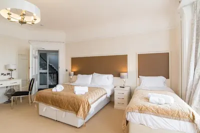 a white bedroom with two beds and a desk at Marine Studios in Aberystwyth