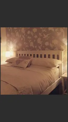 a bedroom with a white bed with floral wallpaper at Ty Mawr Hotel in Llanbedr