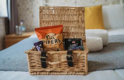 a wicker basket filled with snacks on a bed at Three Wells B&B in Llandrindod Wells