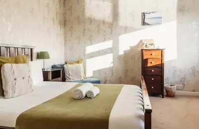 a bedroom with a large bed with a dresser and a chair at Three Wells B&B in Llandrindod Wells