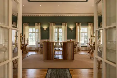 a living room with green walls and a table at Tyddyn Llan Restaurant with Rooms in Corwen