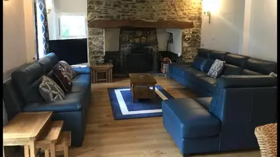 a living room with blue couches and a fireplace at Aberystwyth, Pentre Farmhouse, in Capel Bangor