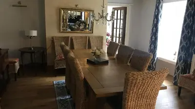 a dining room with a wooden table and wicker chairs at Aberystwyth, Pentre Farmhouse, in Capel Bangor