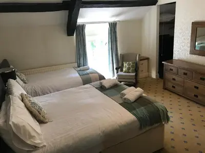 a bedroom with two beds and a chair and a window at Aberystwyth, Pentre Farmhouse, in Capel Bangor