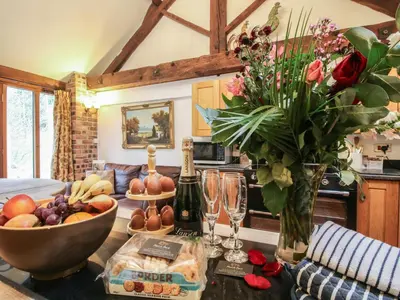 a table with a bowl of fruit and a vase of flowers at Corn House in Plaish