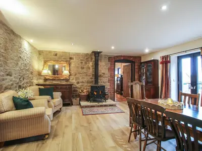 a living room with a table and a fireplace at Corn House in Plaish