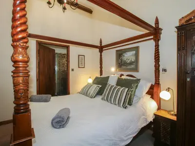 a bedroom with a large wooden canopy bed with pillows at Corn House in Plaish