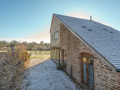 an old brick building with a black roof at Glebe Barn in Caynham