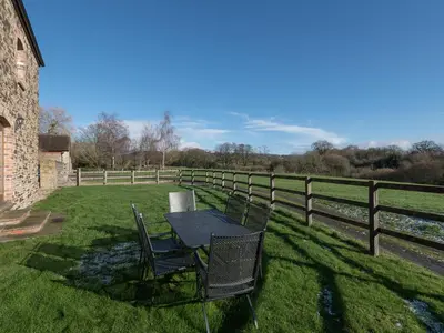 a table and chairs in a field next to a fence at Glebe Barn in Caynham
