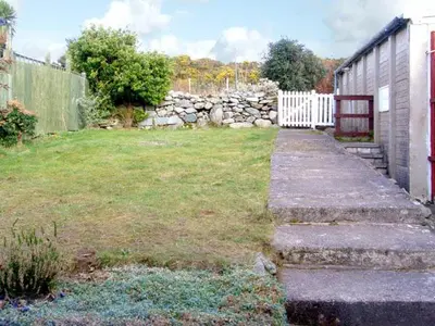 a yard with a white fence and a stone wall at Trem y Mor in Harlech
