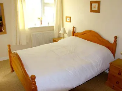 a bedroom with a large white bed with a window at Trem y Mor in Harlech