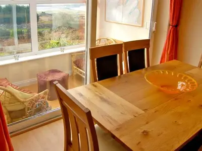 a wooden table and chairs in a room with a window at Trem y Mor in Harlech