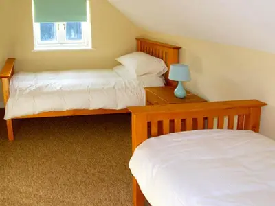 a bedroom with two beds and a lamp on a table at Manor Cottage in Ludlow
