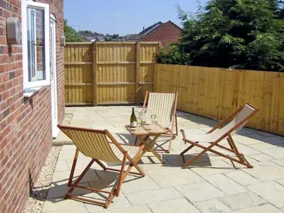 a patio with two chairs and a table with a bottle of wine at Manor Cottage in Ludlow