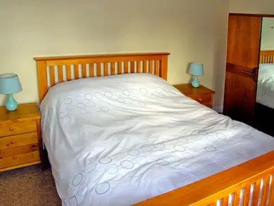 a bedroom with a bed with white sheets and two lamps at Manor Cottage in Ludlow