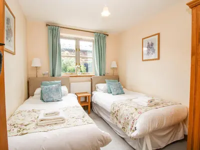 a bedroom with two beds and a window at The Olde Cowshed in Acton Scott
