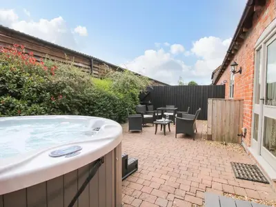 a hot tub in a backyard with a table and chairs at The Olde Cowshed in Acton Scott