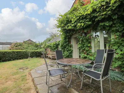 a patio with a table and chairs in front of a house at Old Coach House in Shrawardine