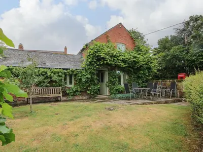 a house with a bench and a table and chairs at Old Coach House in Shrawardine