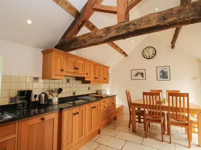 a kitchen with wooden cabinets and a table with chairs at Old Coach House in Shrawardine