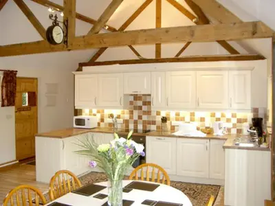 a kitchen with a table with a vase of flowers on it at Happy Union Stables in Abbey-Cwmhir