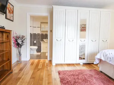 a bedroom with white cabinets and a pink rug at 1 The Beeches in Llangollen
