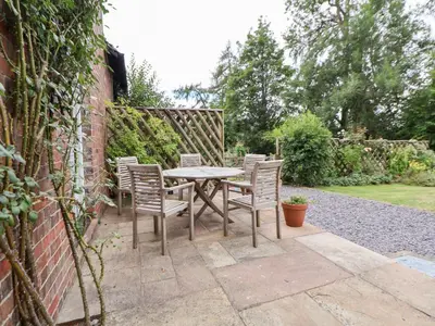a patio with a table and chairs in a garden at Bryn Howell Stables in Trevor