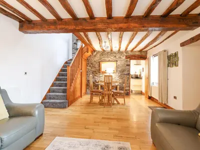 a living room with wooden ceilings and a table and chairs at Isallt in Llanbedr
