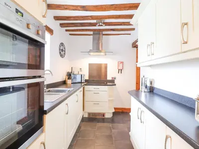 a kitchen with white cabinets and black counter tops at Isallt in Llanbedr