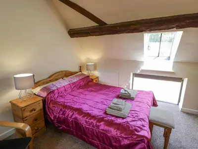 a bedroom with a large bed with a purple bedspread at Betty's Barn in Eaton