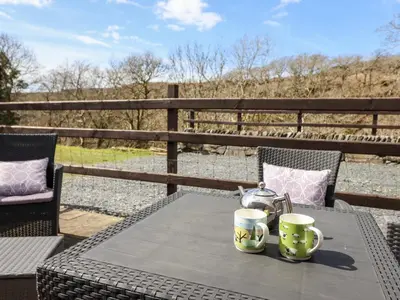 a table with two cups and a tea pot on it at Cwm Yr Afon Cottage in Harlech