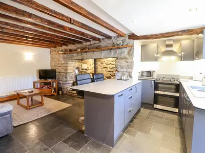 a large kitchen with a stone wall at Cwm Yr Afon Cottage in Harlech