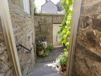 an alley with a door and some potted plants at The School Room in Kington