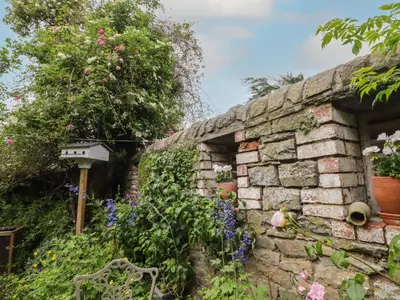 a stone wall with flowers and a bird house at The School Room in Kington